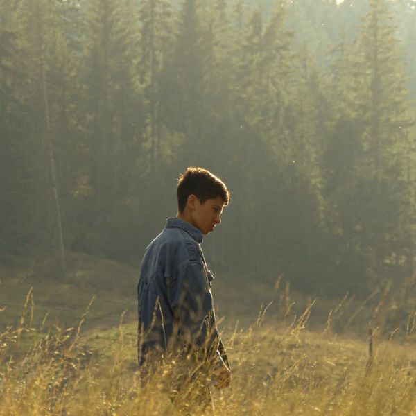 Person meditating peacefully at sunrise with a calm background.